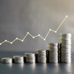 Stack of Thailand coins on black wooden table with profit graph,